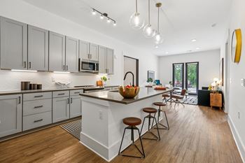 A modern kitchen with a white island and wooden floors.